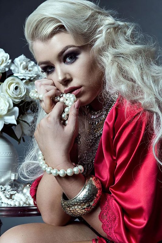A woman holding a pearl necklace while posing