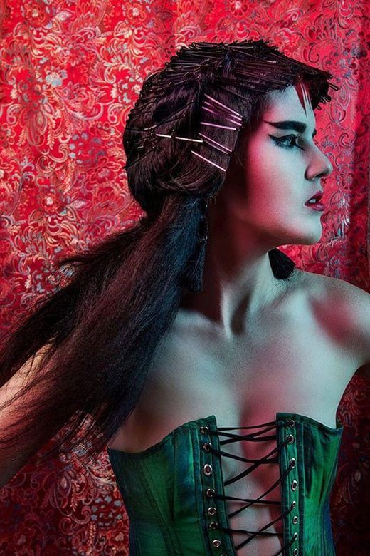 A woman with Ancient Japanese inspired make-up, on a corset, facing her side