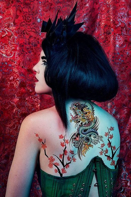 A woman with Ancient Japanese inspired make-up, showing up tattoos in her back