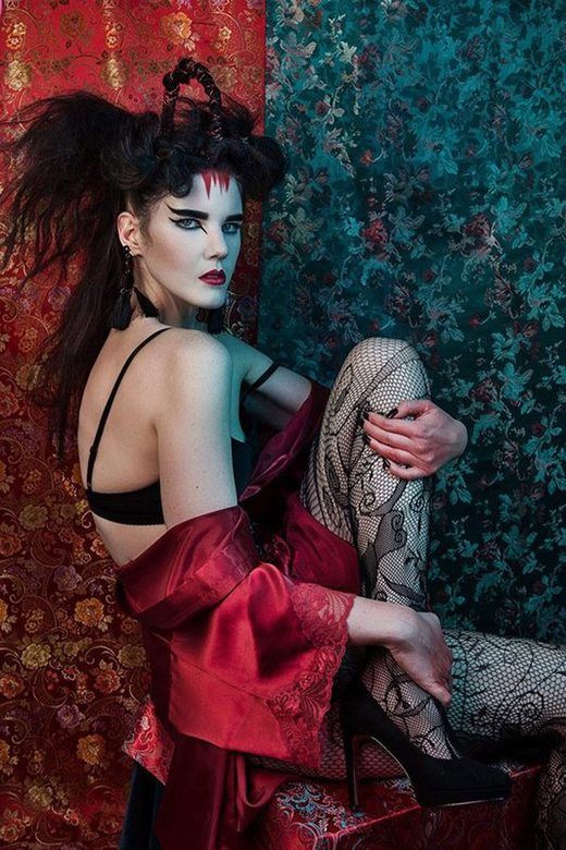 A woman with Ancient Japanese inspired make-up, sitting while posing