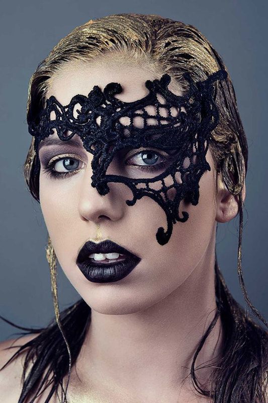 A woman wearing a black half-masquerade mask