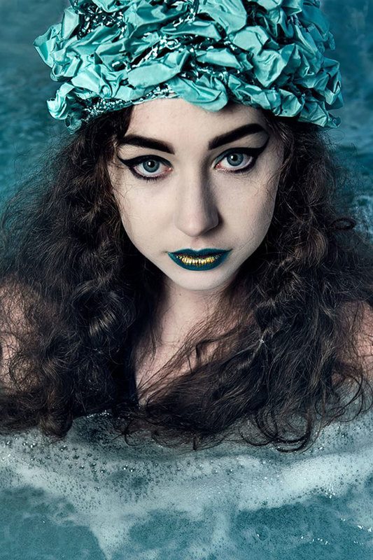 A close up shot of a woman with turquoise headband, while her body is dipped in water