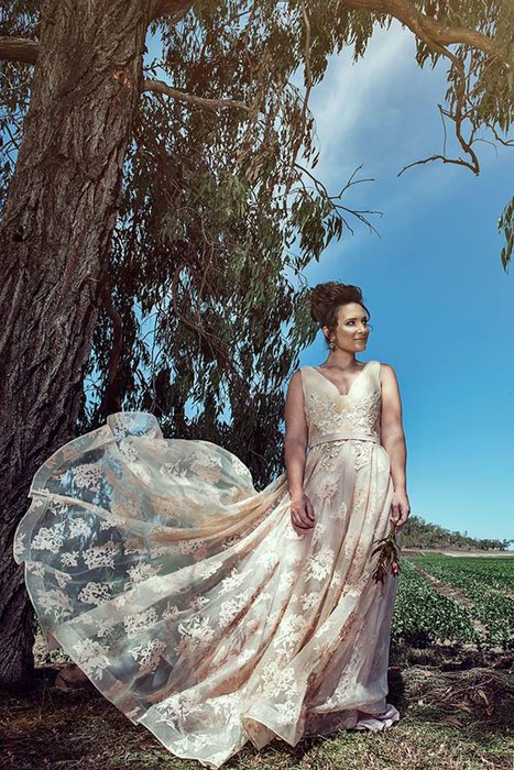 A woman with her white gown being flown by the wind in a farm