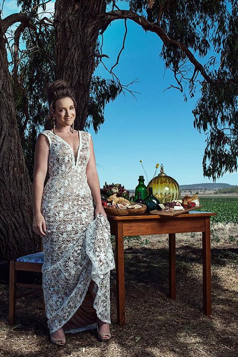 A woman standing beside a table under a tree in a field