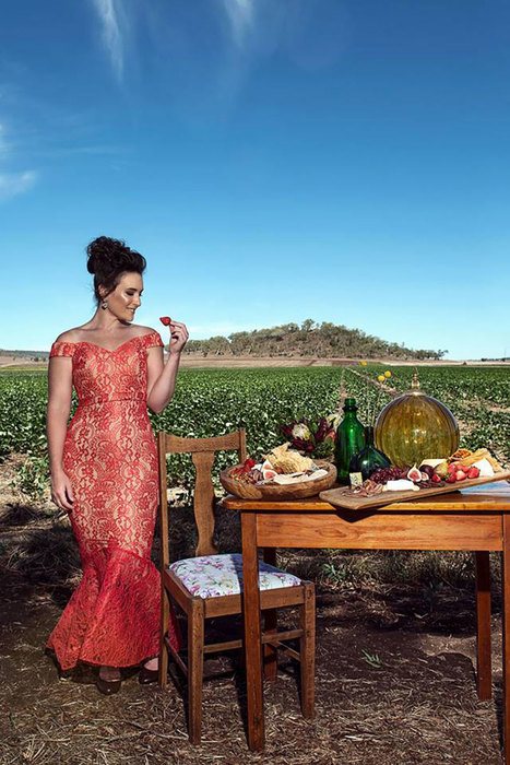 A woman standing and staring on a berry, beside a table set arranged in the middle of a field