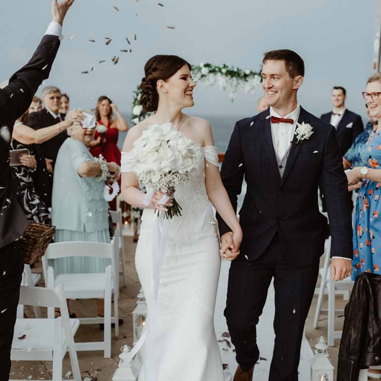 A new married couple walking on the isle while the guests celebrate their wedding