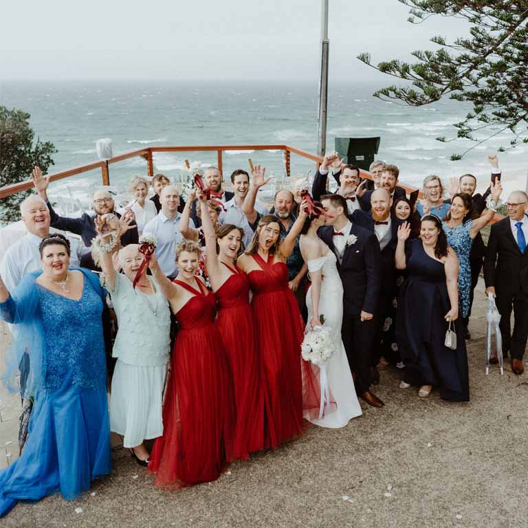 A group photo of the guest celebrating the couple's marriage while the couple kisses
