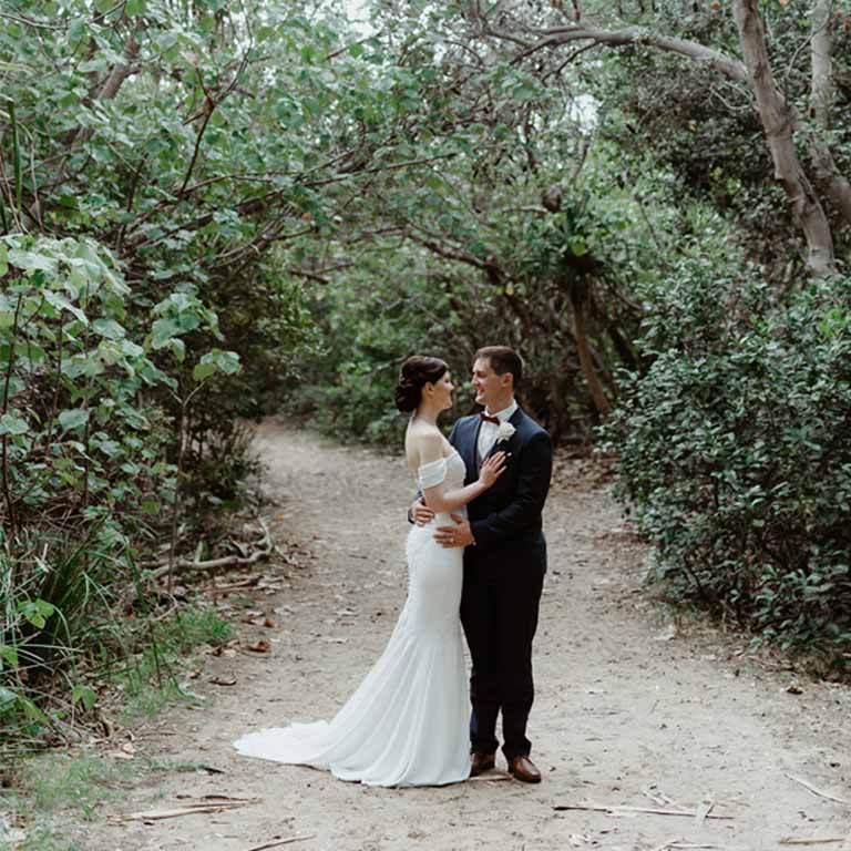 A married couple smiling at each other in the forest trail