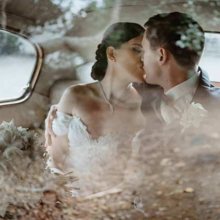 A bride and a groom kissing inside a car