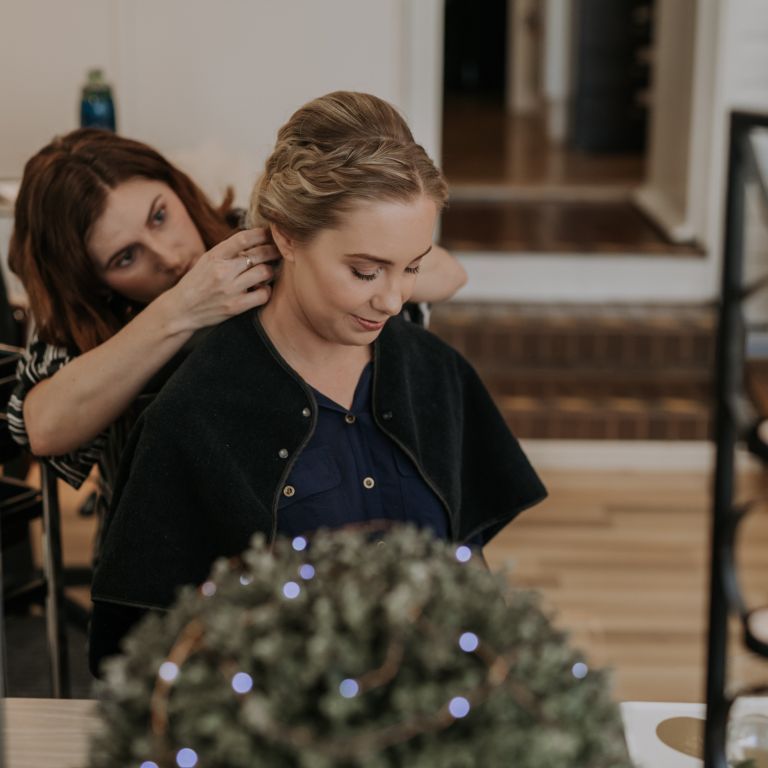 A woman holding and styling another woman's hair