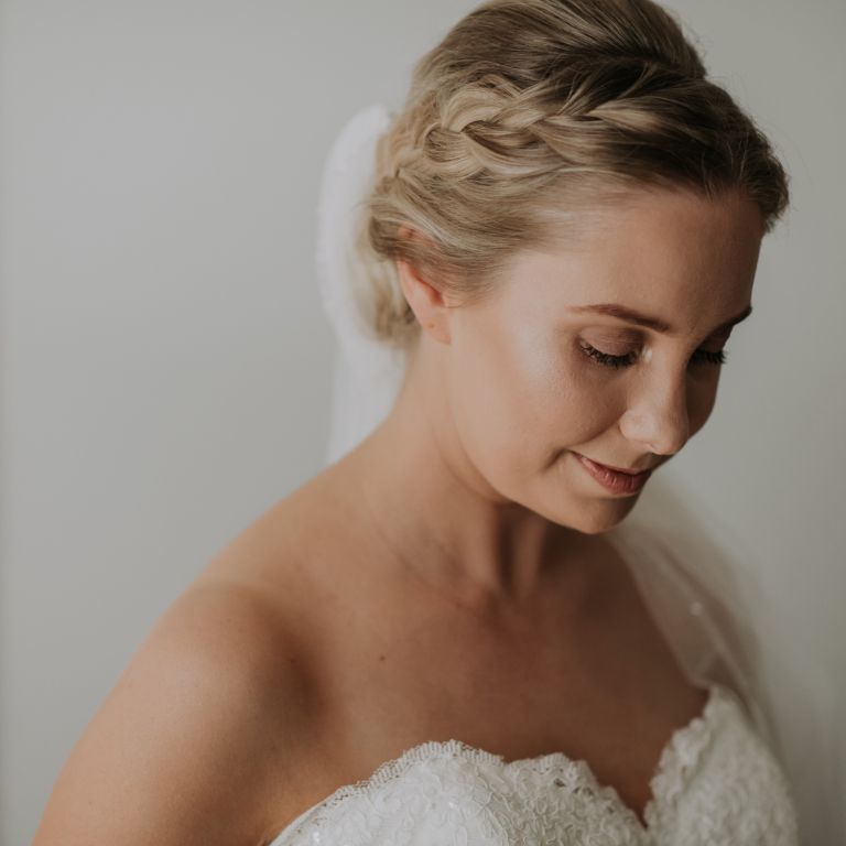 A woman wearing a white gown and veil, looking downwards, side view, close-up
