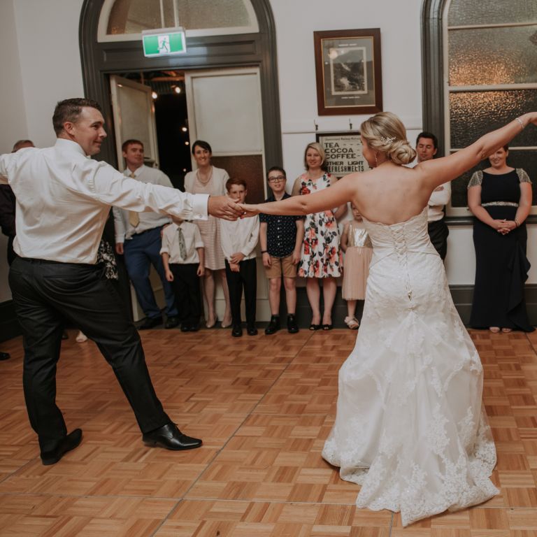 A bride and a groom dancing while people are watching