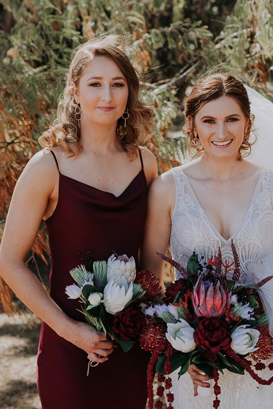 Two woman standing and holding a bouquet dark and white coloured flowers