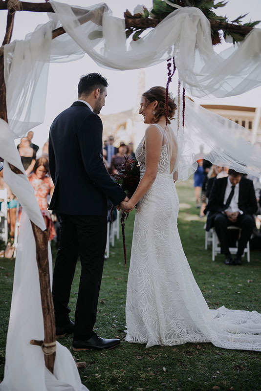A groom and a bride standing, facing the back