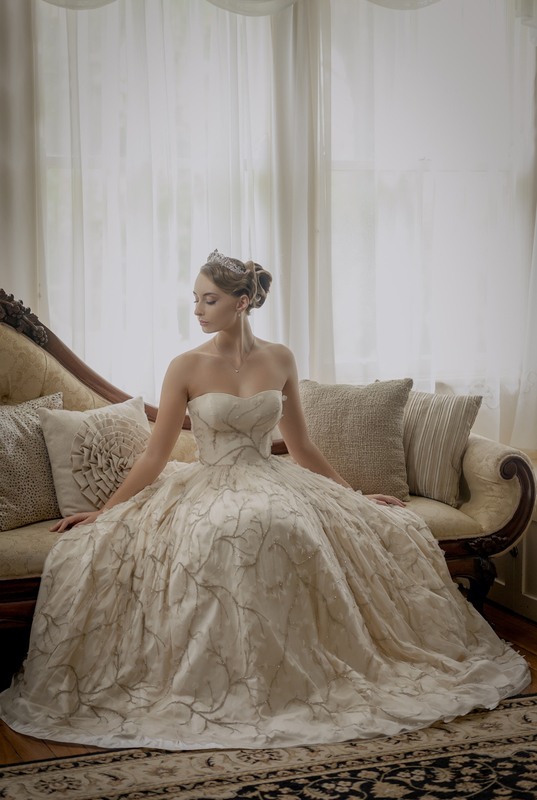 A woman in white gown, sitting on a couch