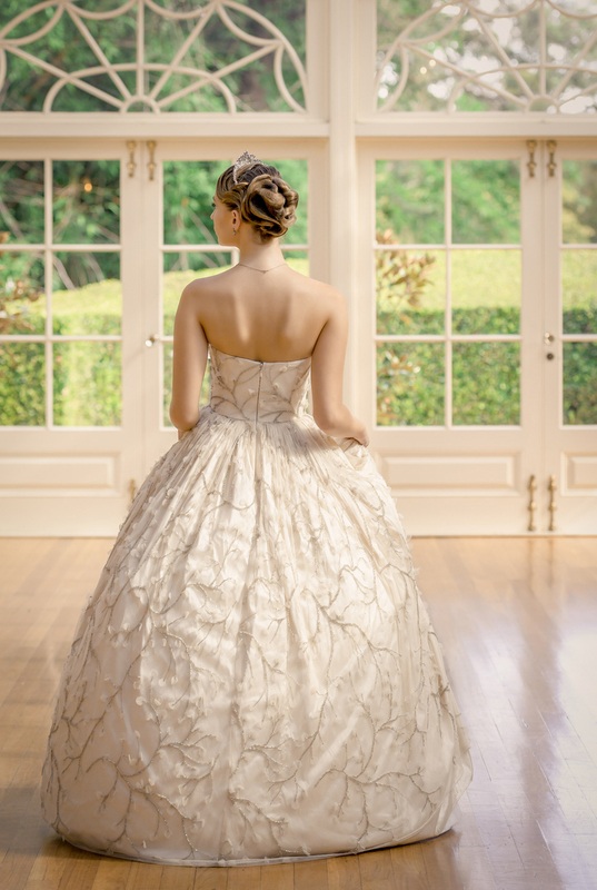 A woman wearing a white ball gown, facing the back