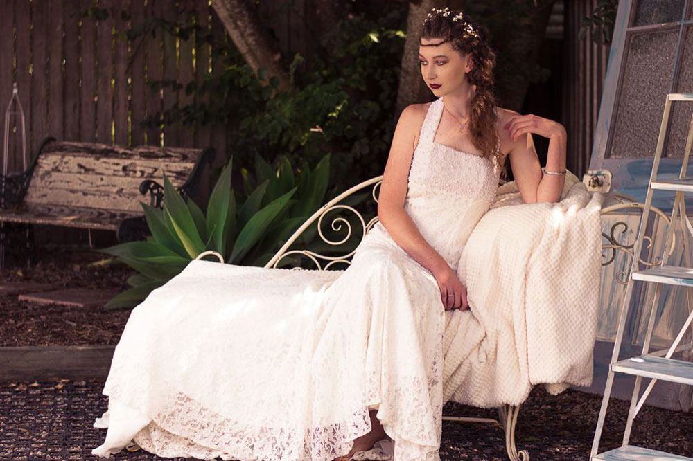 A woman in white gown sitting on a chair, posing