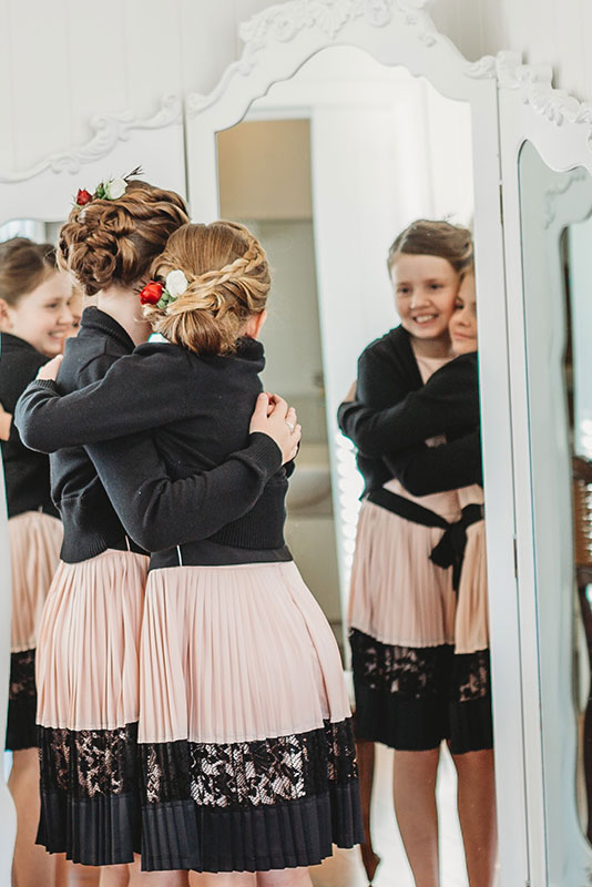 two girls hugging each other while facing a mirror